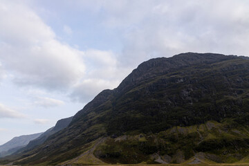 Golden sunset over calm lakes and clear water reflections in The Trossachs and Loch Lomond. Long winding roads cross green hills and mountains in a peaceful, awe-inspiring natural landscape. Exploring