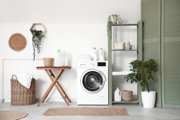 Stylish laundry room with modern washing machine, shelving unit and bottles of detergent