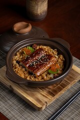 Sizzling unagi rice dish preparation japanese cuisine food photography cozy indoor setting close-up perspective culinary delight