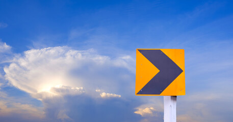 Yellow curve to right warning traffic sign against cloud on blue evening sky background 