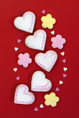 Romantic decorated gingerbread cookies in a shape of hearts and flowers, with small sugar hearts, red background