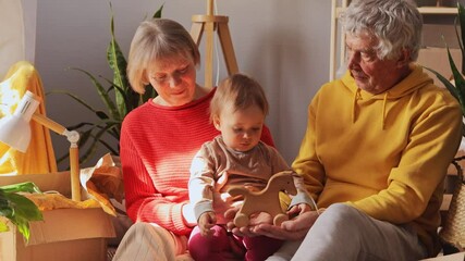 Pensioners share a heartwarming moment with their grandchild, playing with a wooden toy in a comfortable and inviting home setting