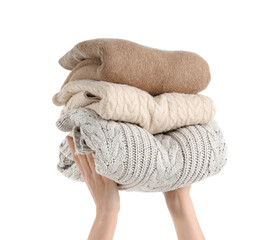 Female hands holding stack of clean clothes on white background