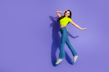 Young woman in casual outfit jumping joyfully on a purple background