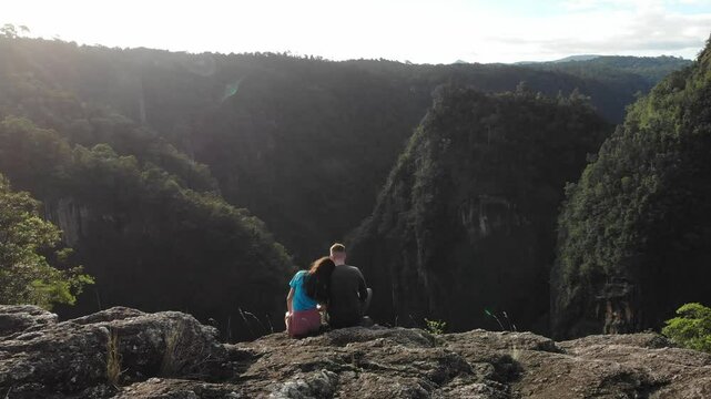 Dramatic aerial view of romantic couple sitting on the edge of deep gorge - Tully Falls and Tully Gorge in Far North Queensland, Australia