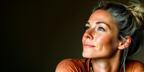 Woman with a serene smile looking upward reflecting maturity and life satisfaction.