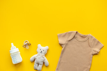 Flat lay with beige baby bodysuit and eco friendly toys, top view. Newborn background