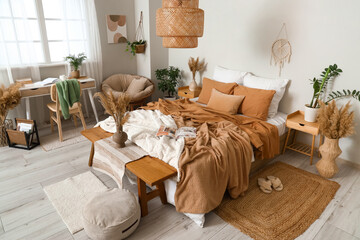 Interior of stylish bedroom with cozy bed, wooden bench and pampas grass