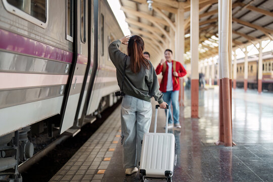 Departure and Anticipation. A woman with a suitcase ready to board her train while friends wave goodbye.