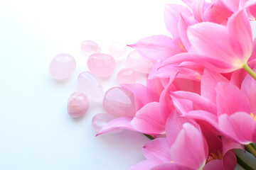 Naklejka premium Beautiful rose quartz crystals and a bouquet of pink tulips. Healing crystals, talisman for women