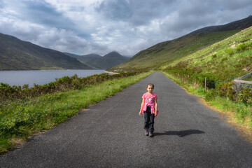 Fototapeta premium A child enjoys serene and peaceful walk along a beautiful and scenic path by a picturesque Silent Valley Reservoir, which is surrounded by lush greenery and majestic Mourne Mountains, Northern Ireland