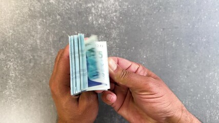 Man counting Pakistan 75 rupees commemorative banknotes