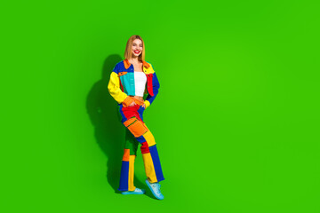 Young woman in vibrant colorful outfit posing against bright green background, expressing creative...