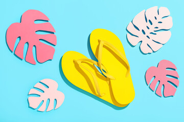Composition with bright flip-flops and decorative palm leaves on color background