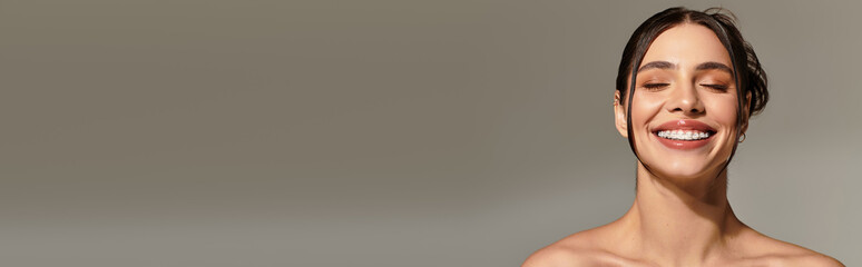 Radiant young woman smiling with joy against a soft neutral background