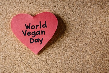 Fototapeta premium Pink heart shape with world vegan day text on cork board on white background