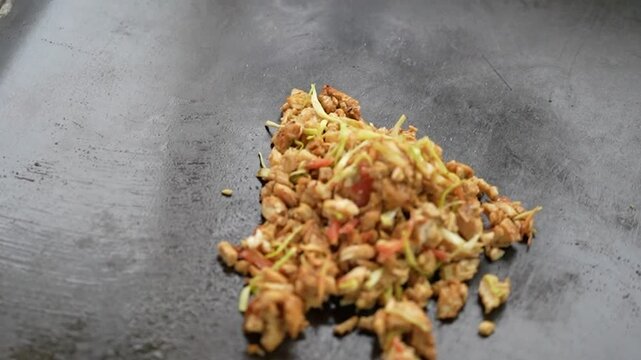 Close-up of seasoned chicken and shredded vegetables stir-fried on a large flat tawa. South and Central Asia, Caucasus
