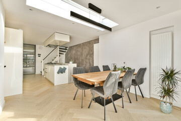 A stylish and airy dining room featuring a wooden table, elegant seating, and natural light streaming in from above. Perfect for gatherings and family meals.