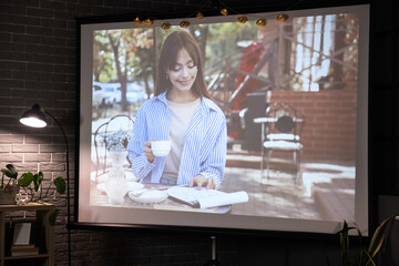 Scene of movie on video projector screen in dark room. Home cinema