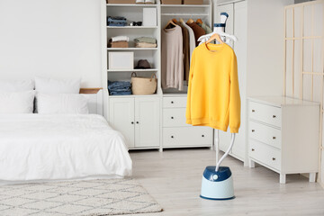 Modern steamer with sweatshirt in bedroom interior