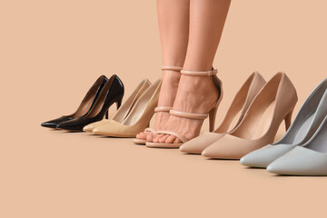 Legs of woman with stylish high heels on beige background, closeup