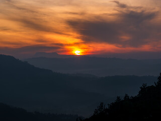 Sun behind the clouds above the mountains