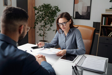 Business meeting of two people man and woman discussing documents with data reports in office