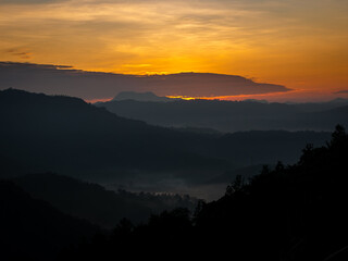 Sun behind the clouds above the mountains