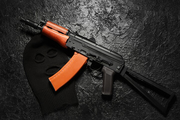 Balaclava with rifle on black grunge background