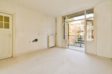 A vacant room featuring a large window that offers a view of outdoor greenery, illuminated by natural light. Ideal for renovation or interior design.