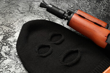 Balaclava with rifle on black grunge background