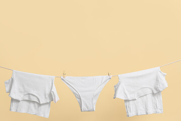 Clean t-shirts and panties hanging on rope against color wall