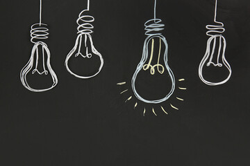 Drawn glowing light bulbs on chalkboard