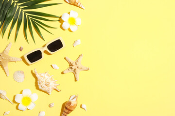 Many sea shells, sunglasses, tropical leaf and flowers on yellow background