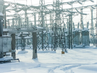 Snowy industrial landscape of electrical substation in winter. Power plant electricity infrastructure. Snowy outdoor scene for energy, engineering and industrial concept.