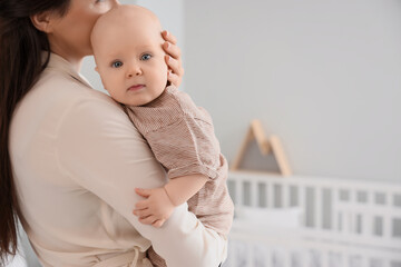 Happy mother hugging her little baby in bedroom, closeup