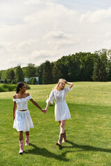 Naklejka premium Young couple walks hand in hand through a sunlit green meadow enjoying their love filled day