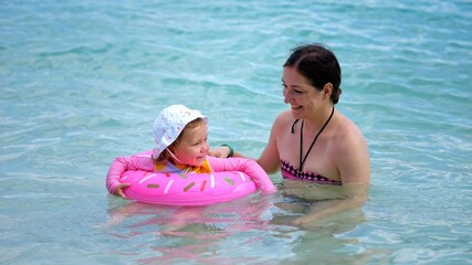 Mother and daughter have fun swimming in sea on hot summer day