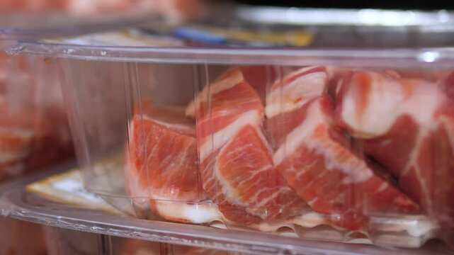 Pristine pork meat pieces neatly arranged in transparent plastic trays, displaying vibrant color and precise packaging within refrigerated grocery store section