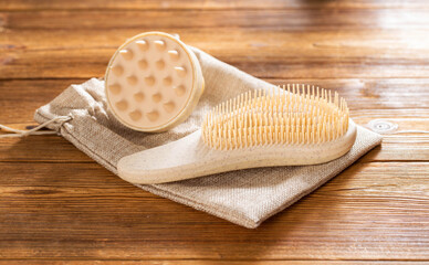 Brown massage comb and scalp massager on wooden background, close-up. Hair care