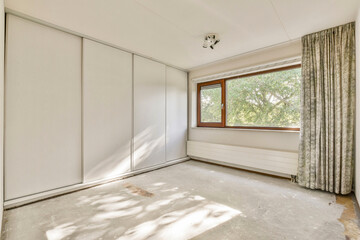 A modern, unfurnished room showcasing large windows that invite natural light, featuring minimalistic design and soft shadows on the floor.
