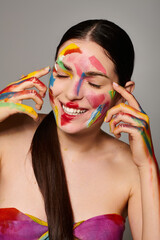 Young beautiful woman expressing joy with vibrant face art and colorful paint designs