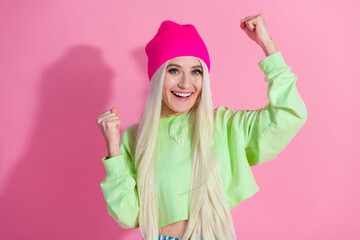 Naklejka premium Stylish young woman in bright trendy casual wear posing with a cheerful expression against a vibrant pink background