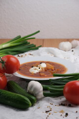 A plate of borscht with sour cream and vegetables and spices. 