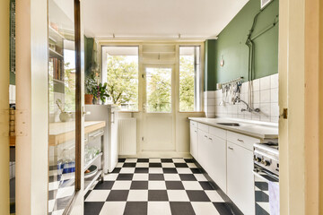 A contemporary kitchen featuring a stylish checkerboard floor and abundant natural light streaming through large windows, creating a fresh and inviting atmosphere.