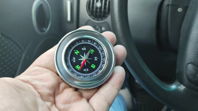 metal compass in hand. silver antique compass.retro compass. terrain orientation. arrow mechanism. circular dial