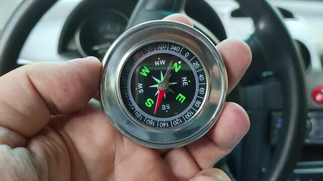 metal compass in hand. silver antique compass.retro compass. terrain orientation. arrow mechanism. circular dial