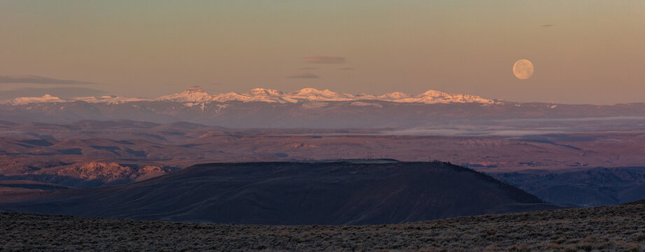 A Waning Gibbous moon is seen at sunrise over Uncompahgre Peak and other snow-covered San Juan Mountains.