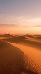 Expansive desert panorama at sunset with glowing orange and pink sand dunes, clear open sky, and tranquil atmosphere