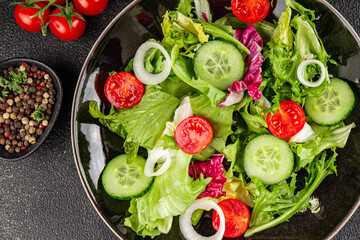 Vegetable salad tomato, cucumber, lettuce, green leaf lettuce, onion appetizer vegetable dish fresh gourmet food background rustic food top view copy space keto and paleo diet vegetarian vegan food